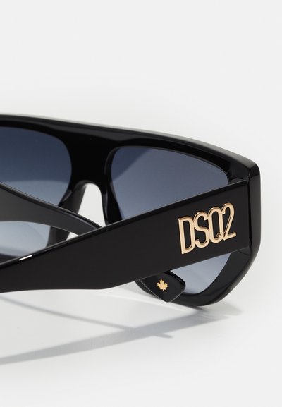 Occhiali da sole neri con lenti grigie, design angolare, logo DSQ2 dorato sul braccio e un piccolo accento di foglia d'acero dorata.