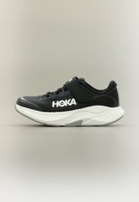 Αθλητικό παπούτσι Hoka σε ασπρόμαυρο χρώμα με ιμάντα Velcro, επάνω μέρος από αναπνέον δίχτυ και παχύ μαλακό πέλμα, εμφανιζόμενο σε πλευρική όψη.