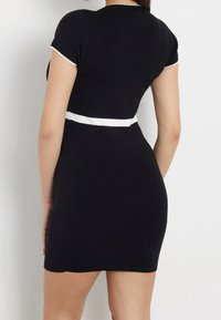 Robe courte noire côtelée avec une coupe ajustée, une bande blanche contrastante à la taille et un bord blanc contrastant sur les manches.