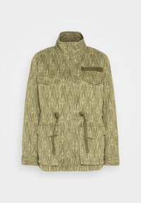 Olijfgroene jas met een getextureerd ikatpatroon. Voorzien van een hoge kraag, vier voorzakken en een trekkoordverstelling in de taille.