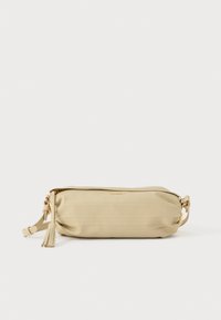 Beežist nahast käekott kuldse tõmbluku ja hobusesaba võtmega, reguleeritava rihmaga, millel on kuldne detail, laotatuna valgel taustal.