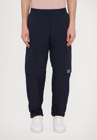 Námorné cargo nohavice vyrobené z ľahkej tkaniny, s elastickým pásom, viacerými vreckami a s logom značky na stehne.