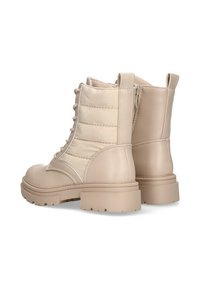 Botines beige con cordones que presentan un diseño de cuero suave, parte superior acolchada de tejido acolchado, suela de goma gruesa y detalle de cremallera en el lateral.