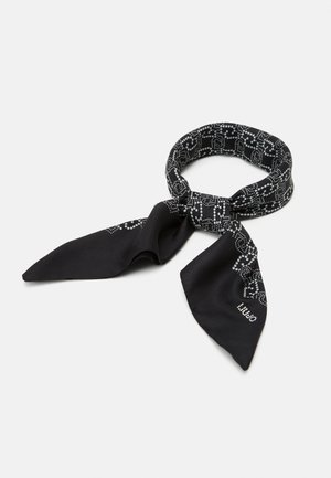 Czarny szalik z tkaniny z białym wzorem łańcuszka w kropki, związany luźnym węzłem z ostro zakończonymi końcami na białym tle.