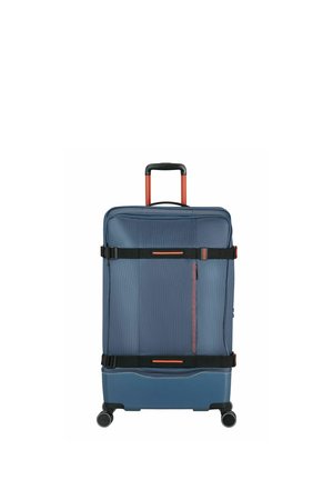 Valise à roulettes bleue avec sangles de compression réglables noires et orange et poignée télescopique déployée.