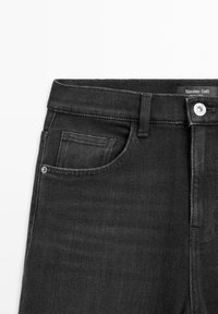Jeans in denim nero con una vestibilità slim, dotati di una tasca frontale, chiusura con bottone silver e un'etichetta del brand in vita. Texture liscia.