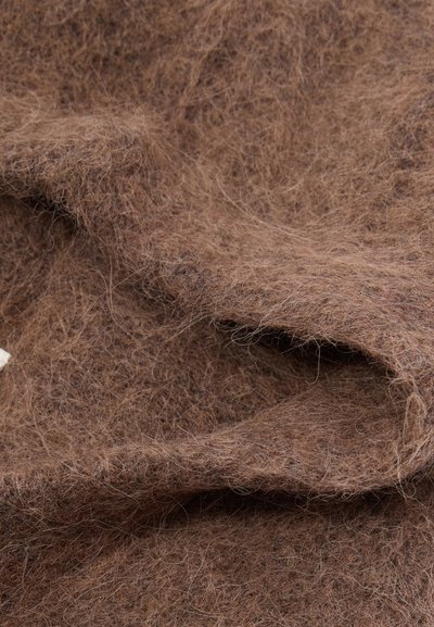 Hnedá plsť s mäkkým, textúrovaným povrchom a jemnými vláknami, zobrazuje vrstvené záhyby a mierne chlpato vyzerajúci vzhľad.