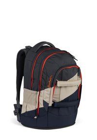 Sac à dos en tissu noir et beige, avec des accents rouges, plusieurs compartiments, des bretelles réglables et un dos rembourré pour plus de confort.