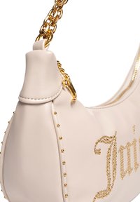 Borsa a tracolla in pelle crema con catena dorata, decorata con borchie dorate lungo la cucitura e chiusura con zip. Dettaglio del logo del marchio molto evidente.