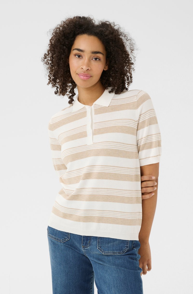 Randig polo skjorta i beige och vitt, med en mjuk stickad textur, korta ärmar och en krage med en knäppning. Matchad med blå jeans.
