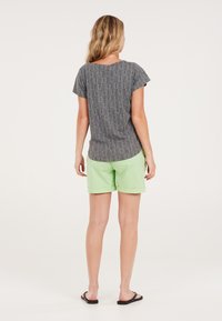 Grijs gestreepte korte mouw top met een ronde hals, gecombineerd met lichtgroene shorts met omgeslagen zomen en zwarte teenslippers.