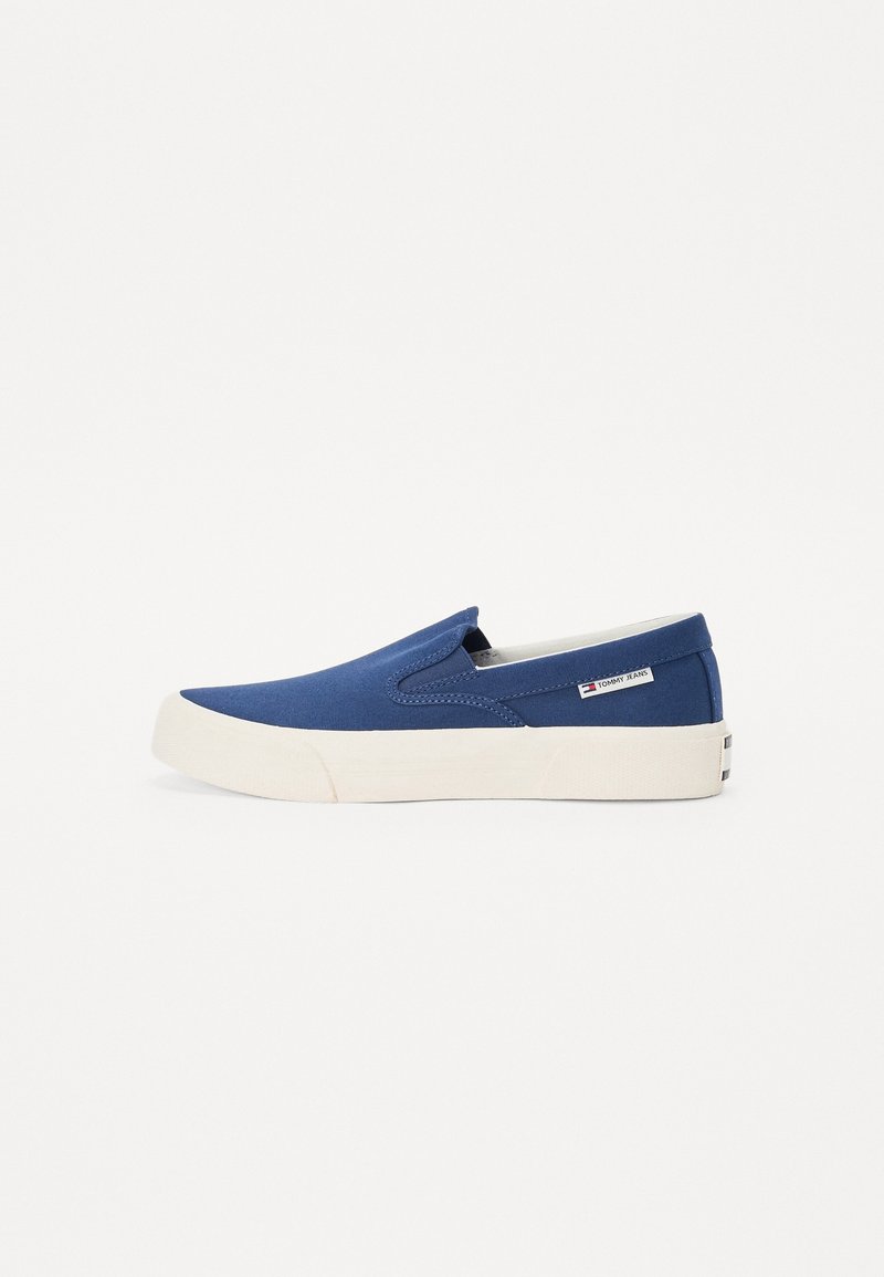 Baskets en toile bleu à enfiler avec une semelle blanche épaisse et un petit logo Tommy Jeans sur le côté et à l'arrière.