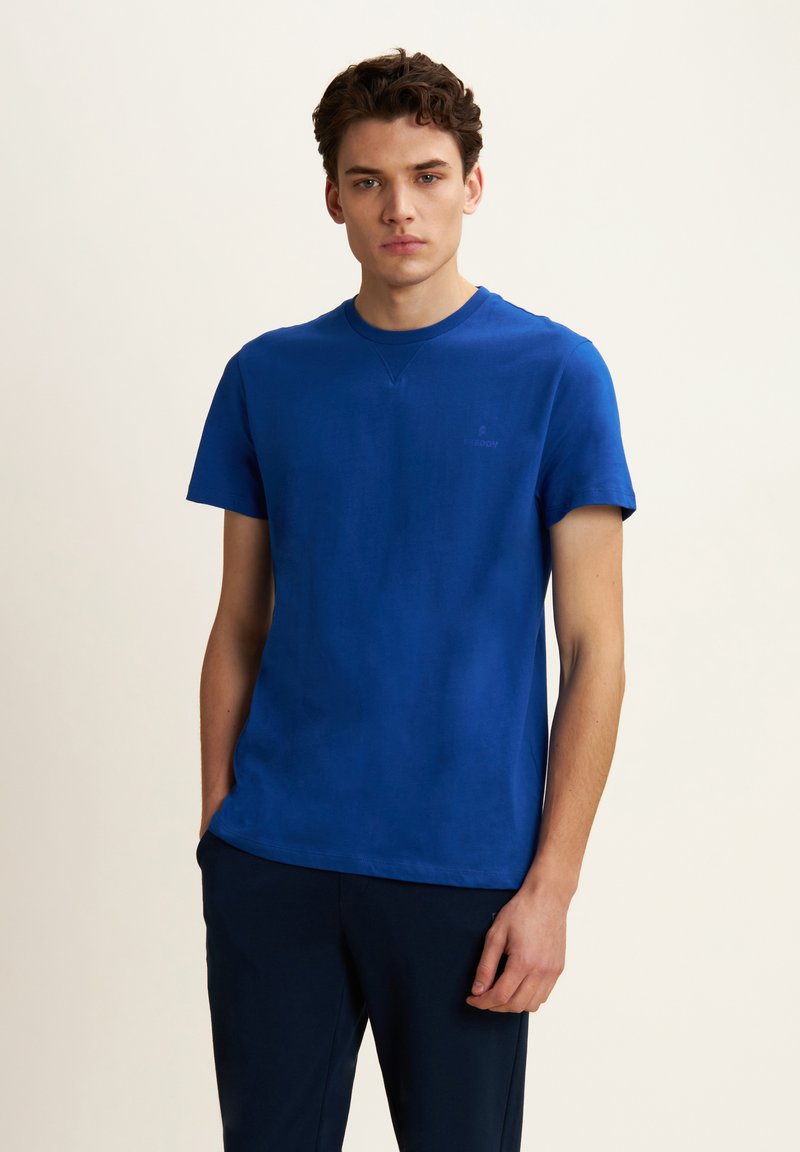 T-shirt in cotone blu con maniche corte, scollatura rotonda e un branding discreto sul petto. Tessuto morbido, vestibilità comoda e colore uniforme.