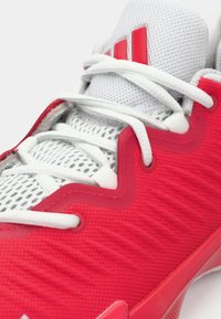 Rode sportschoen met een gestructureerde mesh bovenkant, witte veters en rode accenten. Voorzien van een dempende zool en kenmerkende branding.