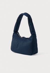 Navy blue, padded shoulder bag with a curved handle and front zipper closure; soft texture and streamlined shape.