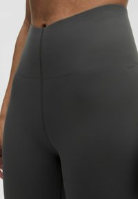 Leggings neri a vita alta realizzati in un tessuto liscio e elasticizzato, con un design senza cuciture e cuciture minime lungo la vita.