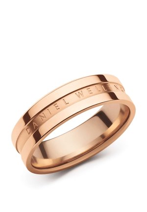 Roségoldener Metallring mit einer Rille um das Band und eingraviertem Text „"DANIEL WELLINGTON"“ auf der Außenseite.