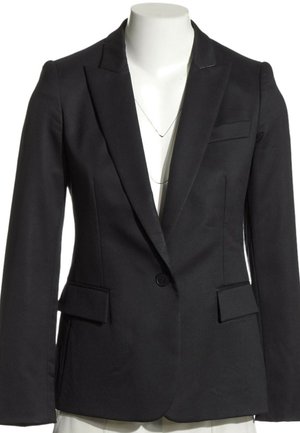 Blazer noir sur mesure à un bouton avec revers crantés et poches à rabats, présenté sur un buste de mannequin blanc.