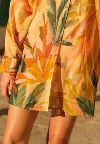 Camicia a maniche lunghe in tessuto leggero e strutturato con un vivace motivo floreale nei toni dell'arancione, del rosa e del verde, dotata di chiusura a bottoni e vestibilità rilassata.