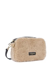 Pochette in pelliccia sintetica beige con dettagli neri, forma rettangolare, chiusura con zip e hardware color oro. Presenta una patch del logo sul fronte.