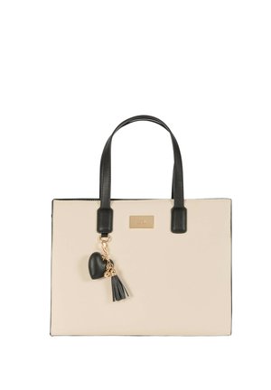 Borsa rettangolare beige con manici neri e un portachiavi a cuore nero con nappina appeso a un manico.