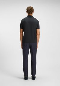 Mørkegrå polo-shirt med korte ærmer kombineret med navy bukser. Glat tekstur, klassisk krave og enkelt design. Footwear er mørkt og afslappet.