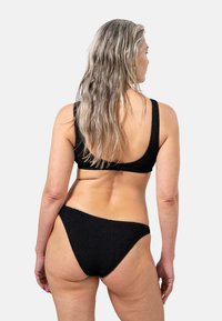 Zwarte textuur bikini met een uitgesneden rug en brede schouderbanden, met een minimalistisch ontwerp en een low-rise onderkant.