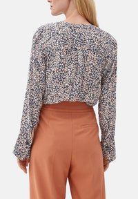 Krótka, kwiatowa bluzka z długimi rękawami; małe, wielokolorowe wzory na ciemnym tle. Miękka tkanina, okrągły dekolt i marszczony detal na plecach.