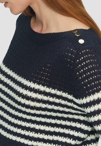Marineblauer gestrickter Pullover mit weißen horizontalen Streifen. Verfügt über eine offene Struktur, einen gerippten Halsausschnitt und drei dekorative Knöpfe an der Schulter.