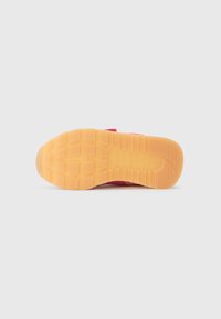 Sneaker sole with a rubber material in light brown, featuring a textured grip pattern and a pink upper section intersecting the sole.
