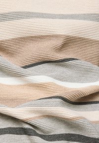 Weiches gestricktes Material mit horizontalen Streifen in Beige, Creme, Grau und Schwarz, das strukturierte Falten und Risse zeigt.