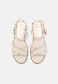 Beige sandals with crisscross straps and an ankle buckle. Smooth leather-like texture and cushioned footbed with gold accents. Size 37.