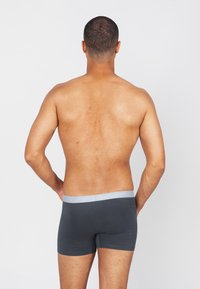 Grijze katoenen boxer briefs met een lichtgrijze tailleband, aansluitend ontwerp en een gladde textuur, weergegeven van achteren.