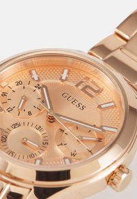 Montre en métal rose gold avec un cadran texturé, trois sous-cadrans et des index horaires audacieux ; bracelet en métal lié avec une finition poli.