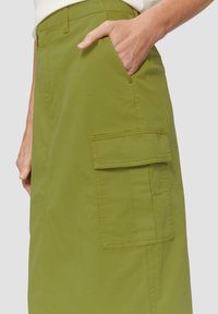 Jupe vert kaki en tissu léger, dotée d'une poche latérale et de détails de couture le long des coutures. Design mi-long.