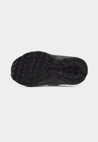 Μαύρη εξωτερική σόλα από καουτσούκ ενός αθλητικού παπουτσιού New Balance με υφασμένα μοτίβα πέλματος και το όνομα της μάρκας ανάγλυφο στο κέντρο.