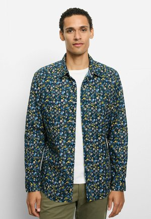 Blau gemustertes Hemd mit kleinen bunten Blumen. Lange Ärmel, Hemdkragen mit Knöpfen und gerader Saum. Weißes Unterhemd sichtbar.