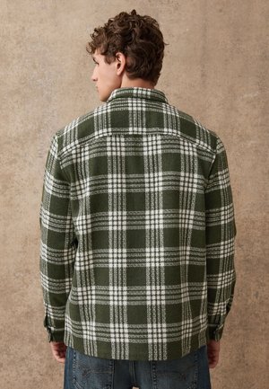 Camicia a quadri verde e bianca con colletto classico, maniche lunghe e tessuto morbido e testurizzato, con polsini abbottonati e orlo dritto.