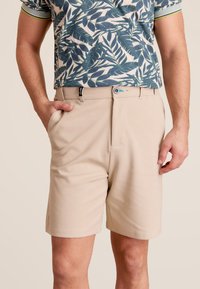 Beige shorts met een vlakke voorkant, zijzakken en een riemlus. Gemaakt van gladde stof, met een minimalistisch ontwerp en een veilige sluiting.