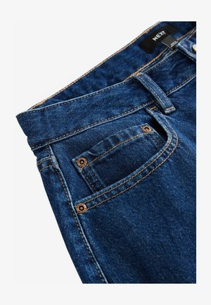 Tmavě modré džínové kalhoty s měděnými akcenty, viditelným šitím a malou přední kapsou. Na etiketě je nápis "NEXT."