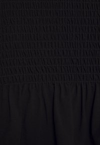 Tela negra con detalles de fruncido texturizado. Presenta secciones recogidas, caída suave y costuras uniformes en toda su extensión.
