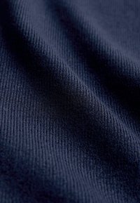 Tmavomodrá rebrovaná látka s textúrovaným povrchom, ktorá zobrazuje jemné vertikálne línie a má mäkký vzhľad. Ideálna na odevy alebo čalúnenie.