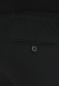 Czarne spodnie o gładkiej strukturze, z elastyczną talią i tylną kieszenią zapinaną na czarny guzik.