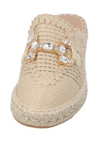Scarpa slip-on in espadrilles beige intrecciato con bordo arricciato, adornata con accessori in oro e strass trasparenti lungo il design superiore.