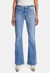 Jeans a zampa d'elefante di colore blu chiaro, realizzati in denim, con cinque tasche, apertura con zip e una texture morbida. Abbinati a stivaletti con motivo.