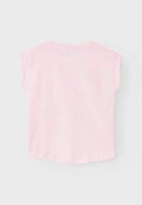 Camiseta de manga corta color rosa claro con un escote redondeado, textura suave y un dobladillo curvado. No se observan patrones ni acentos adicionales.