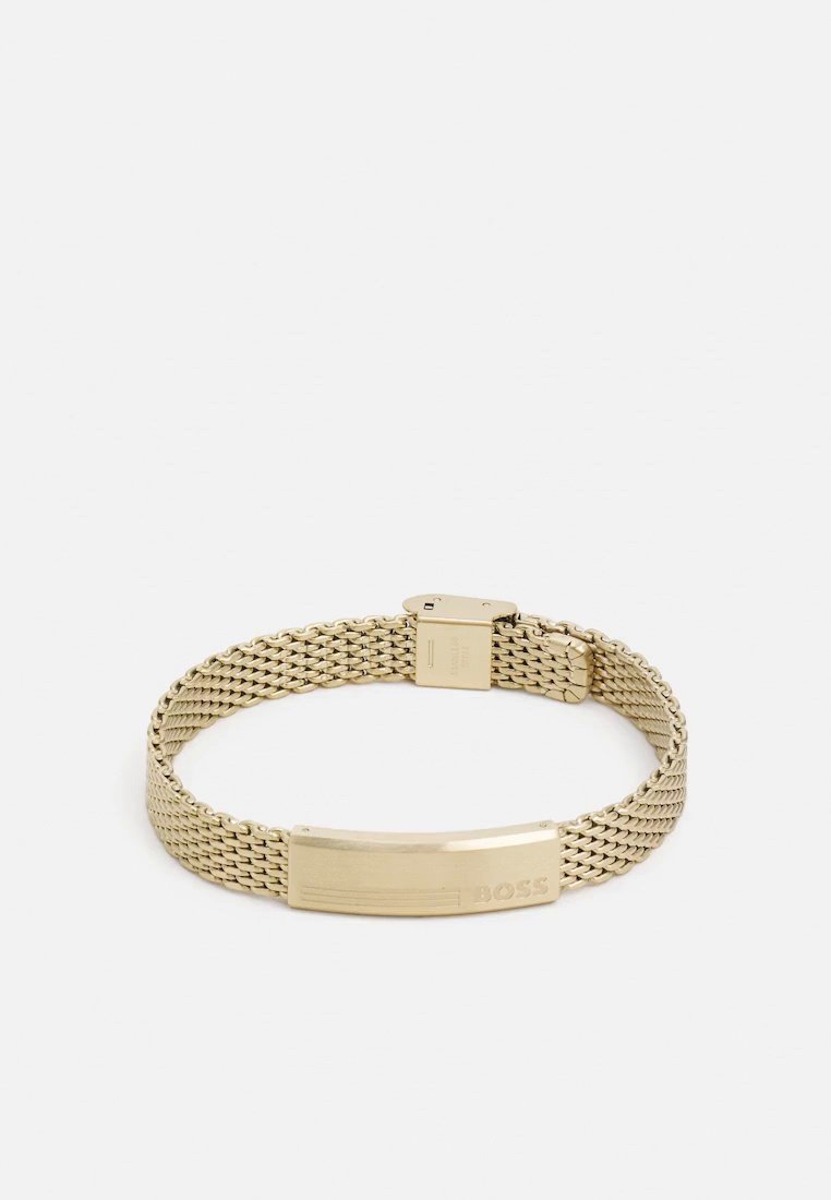 Bracelet BOSS de ton doré, doté d’un bracelet en maille tissée et d’une plaque rectangulaire avec le logo, présenté sur un fond blanc uni.