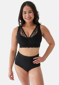Schwarzer Spitzen-Bralette mit tiefem Ausschnitt und breiten Trägern, kombiniert mit hoch tailliertem schwarzen Unterwäsche. Glatter Stoff und zarte Spitzen-Details.
