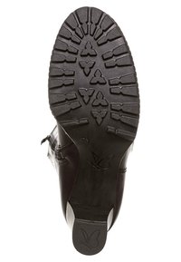 Suela de bota de cuero negro con un patrón de textura en la banda de rodadura, que presenta un logo central y surcos para tracción. Forma redondeada con un acabado suave.