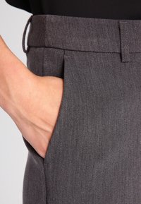 Szare dopasowane spodnie o gładkiej fakturze, z boczną kieszenią i płaskim przodem. Pas jest lekko podwyższony i ma minimalistyczny design.